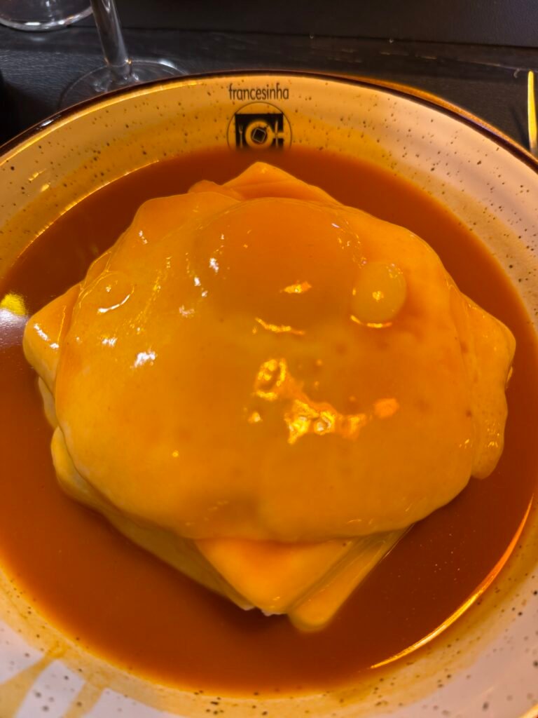 Francesinha do Francesinha Café no Porto com molho picante, batatas fritas e ovo estrelado
